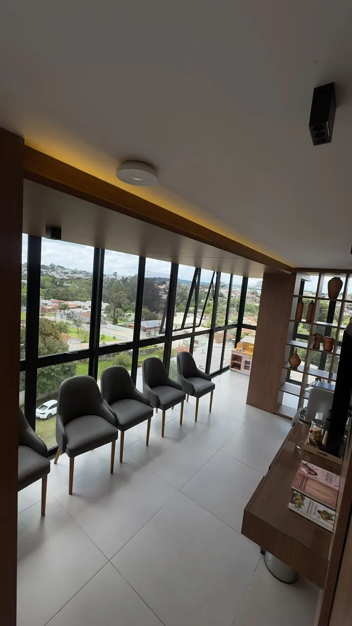 Sala de espera da Ocker Medicina Integrada, com poltronas diante da janela e vista de Mafra