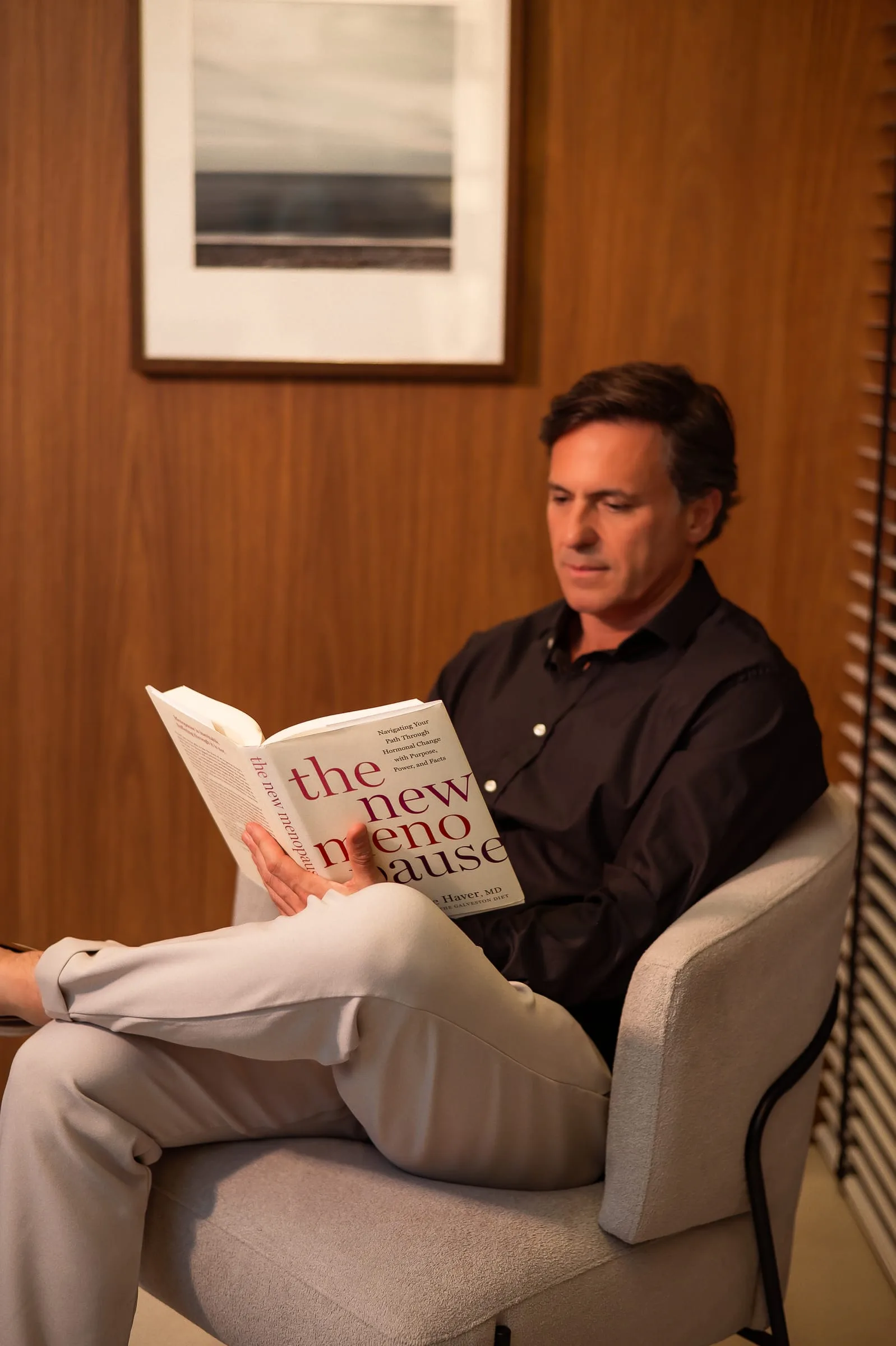 Dr. Guilherme Ocker lendo na poltrona do consultório da Ocker Medicina Integrada