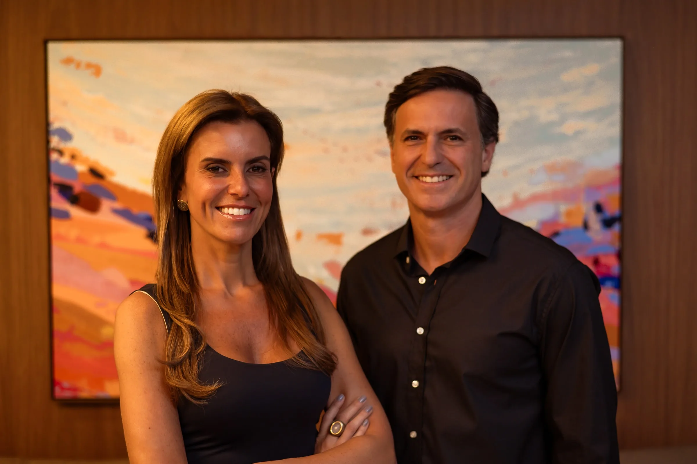 Dr. Guilherme Ocker e Dra. Juliana Ocker diante de um quadro na Ocker Medicina Integrada